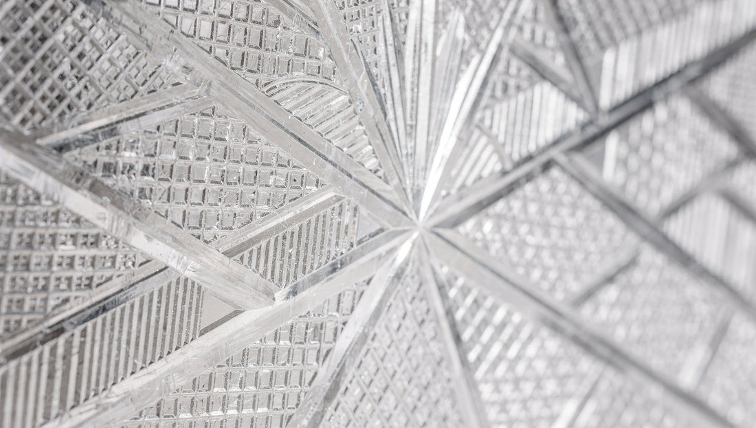 Close view of intersecting cut lines on a glass wall, grid-like, on pale grey.