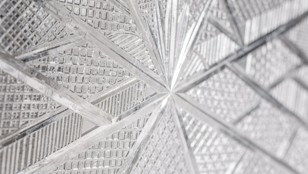 Close view of intersecting cut lines on a glass wall, grid-like, on pale grey.