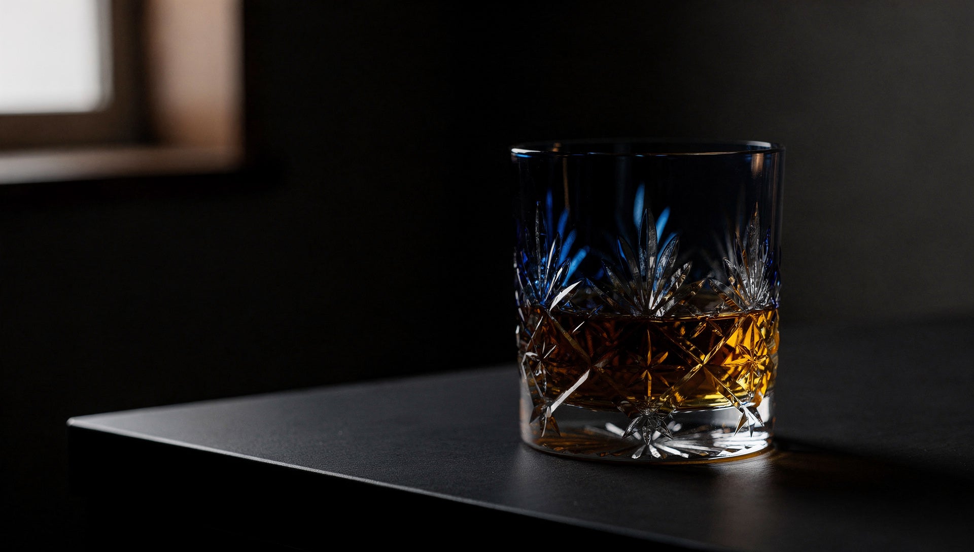 One smoke or cobalt Japanese cut-glass rocks glass in evening light on an ink ground.