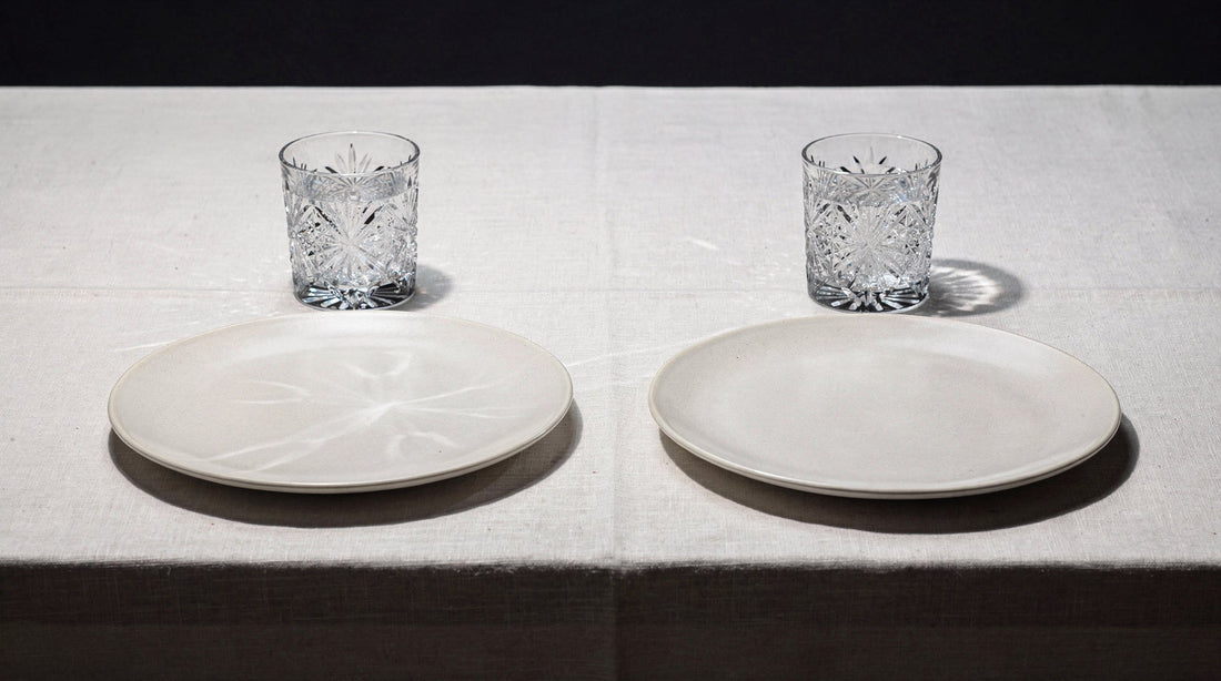 Two quiet place settings, each with one Japanese cut glass and a plain plate