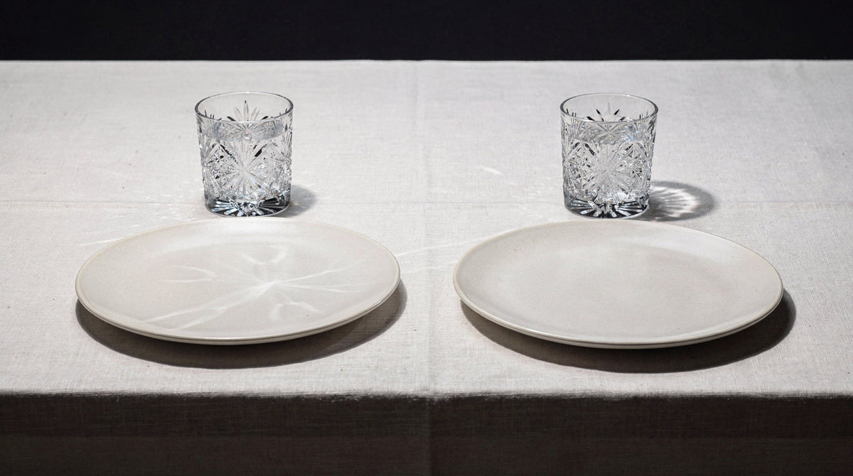 Zwei stille Gedecke, jedes mit einem japanischen Schliffglas und einem schlichten Teller