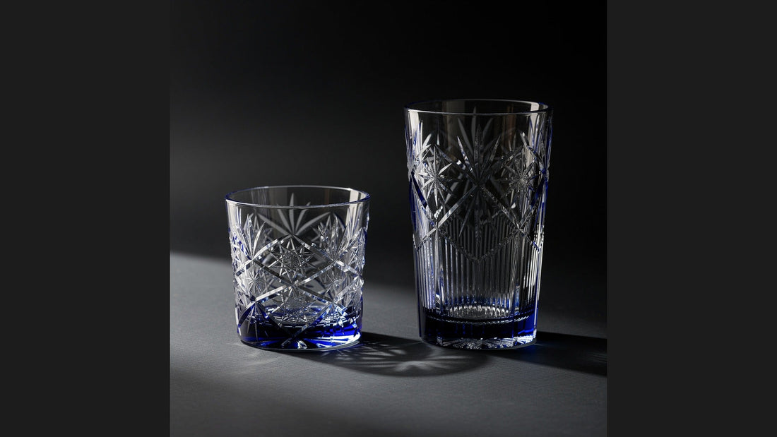 An empty rocks glass beside an empty tall tumbler on an ink ground