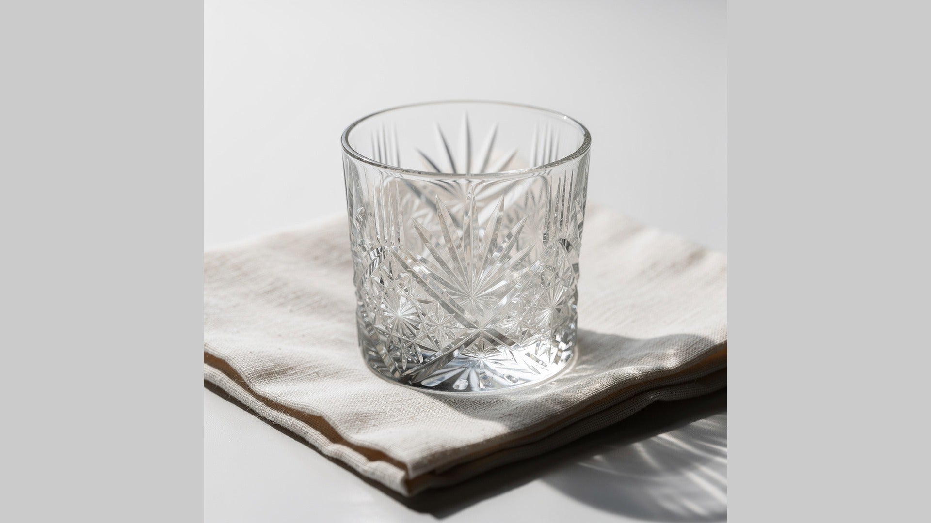 A clear Japanese cut-glass rocks glass drying on pale linen