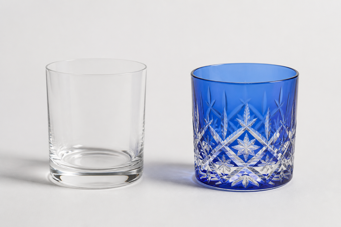 Clear thin whisky tumbler beside a cobalt Japanese cut rocks glass on pale ground