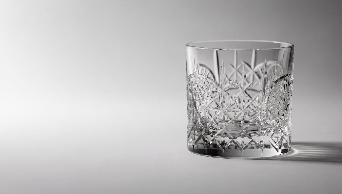 Un verre à whisky japonais taillé, transparent, dans la lumière d'une fenêtre, les facettes se lisant comme un filet lumineux.