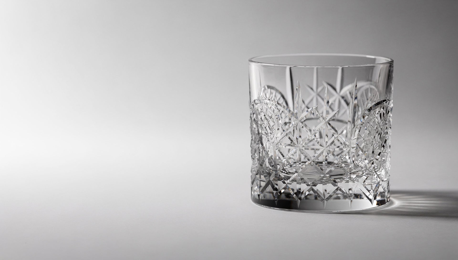 One clear Japanese cut whiskey glass in window light, facets reading as a bright net.